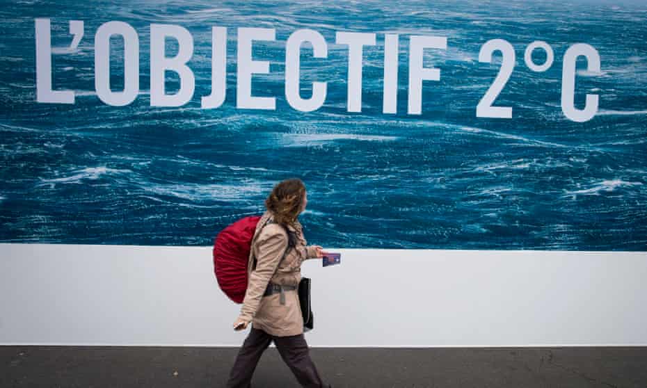 A woman walks in front of a poster saying ‘Objective 2 degrees’
