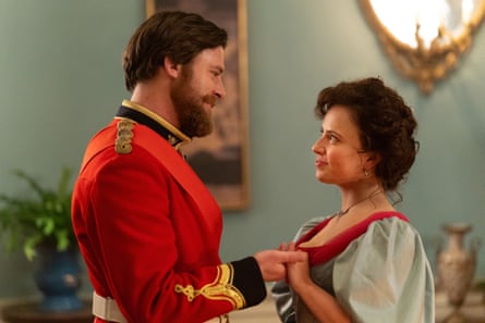 A man in a red military uniform holding the hand of a woman in an evening dress