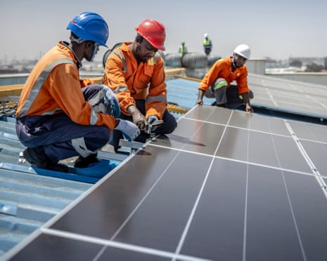 Technicians install solar panels on a factory roof in Nairobi, Kenya.