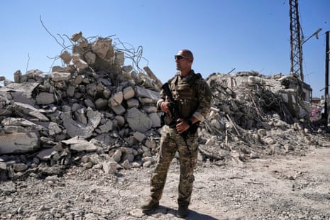 An armed Lebanese soldier stands in front of a destroyed house in Zawtar al-Gharbieh.