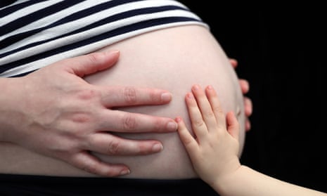 child placing a hand on the stomach of a pregnant woman