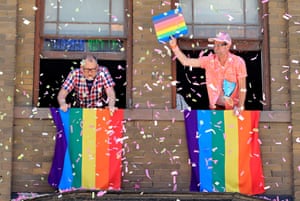 People display rainbow flags from their apartment windows as confetti falls around them, during a Pride festival in Toronto