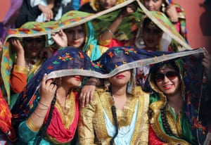 Women wearing traditional Punjabi attire shield themselves from the sun in Amritsar, India