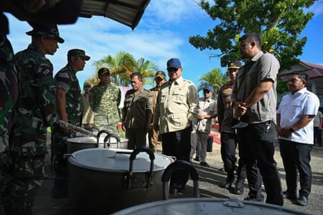 Indonesia’s President Prabowo Subianto (C) inspects the operation of a public kitchen preparing food for flash flood survivors at an evacuation post in Pandan, Central Tapanuli, in the North Sumatra province.
