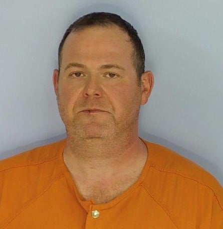 Man in orange shirt looks straight ahead