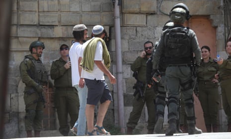 Jewish settlers under the protection of Israeli police, walk through occupied Hebron on 25 April.