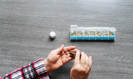 A person takes pills from a pill container 