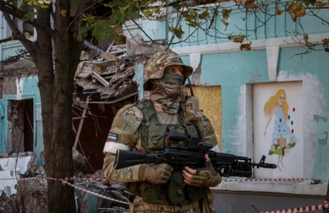 A picture taken during a visit to Mariupol organized by the Russian military shows a Russian serviceman on guard in front of a school.