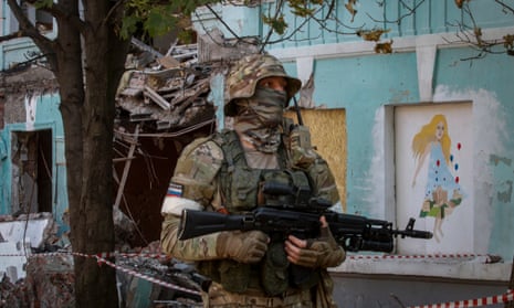A Russian serviceman next to a school destroyed by shelling in downtown Donetsk