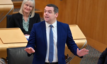 Douglas Ross gesturing with both hands as he stands at his desk to address the chamber