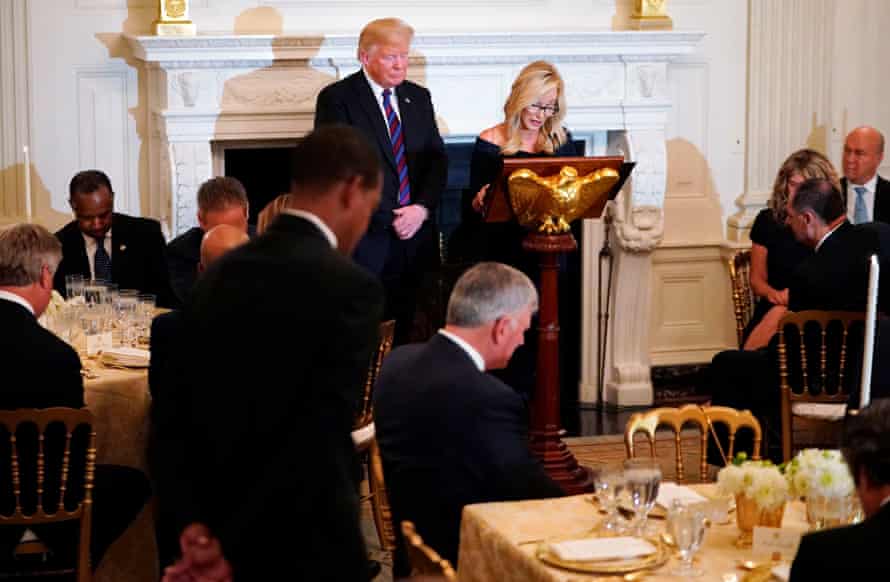 Trump listens as Paula White leads a prayer at a dinner celebrating evangelical leadership in the State Dining Room of the White House in August.
