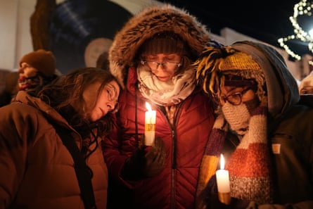 people stand close together while holding candles