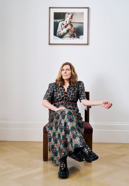 Rose Boyt sitting in a chair beneath a photograph of her father, photographed by Suki Dhanda for the Observer New Review. Hair and makeup by Juliana Sergot.