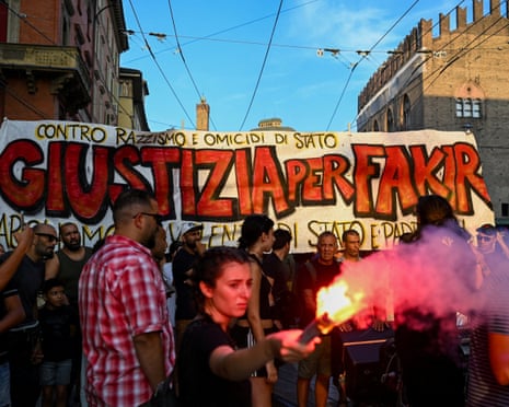 A protester holds a flare in front of a banner reading in Italian "Justice for Fakir" during a protest following the death of Abderrahim Fakir in Bologna, Italy.