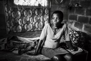 Paulina, 19, sits in the room she shares with other family members in Nyaje village