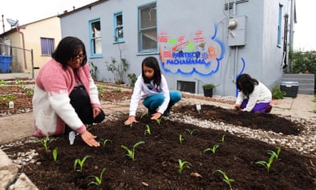 Martha Escudero, left, plants corn in the backyard of her reclaimed home with her daughters Meztli, right, and Victoria.