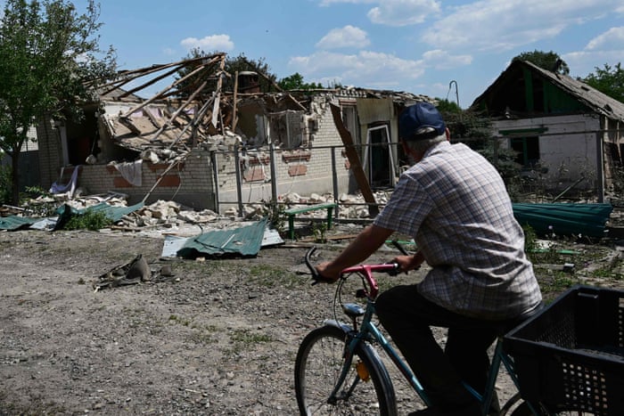 A cyclist rides past a destroyed house that was hit during an airstrike in northern Sloviansk.