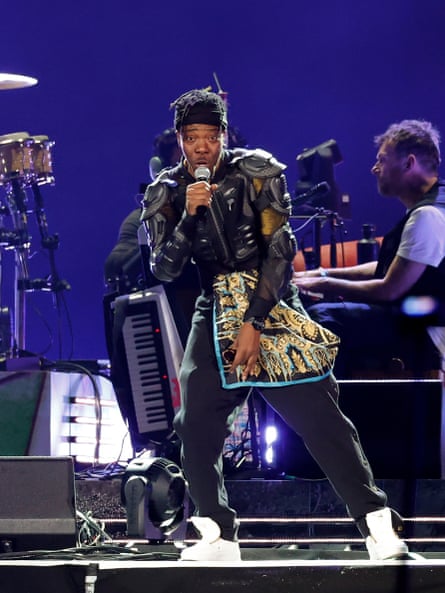 a man performing on stage with a band in the background