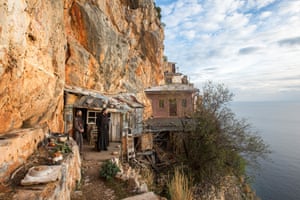 Monks look out from their cell which clings to the cliffs of Karoulia