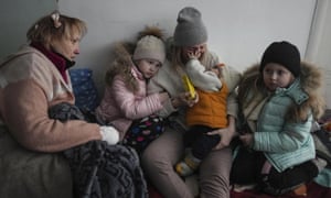 Women and children sit on the floor of a corridor in a hospital in Mariupol, eastern Ukraine.