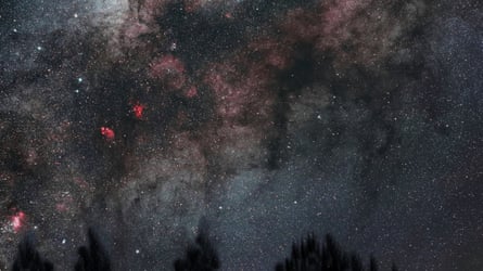 Stars shine in a red, pink and black night sky