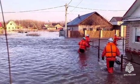 This photo taken from a video released by the Russian Emergency Situations Ministry on April 6, 2024 shows rescuers walking across a flooded street on their way to evacuate residents during a flood in the town of Orsk, Orenburg region, southeast of the southern tip of the Ural Mountains.