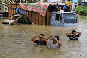 لوكسكون ، إندونيسيا ، يمر الناس عبر شاحنة غارقة في المياه عالقة في مياه الفيضانات في شمال آيس بعد هطول أمطار غزيرة في المنطقة
