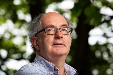 Headshot of writer John Lanchester against a background of blurry leaves and sky
