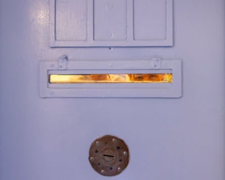 Two men look through the window in their cell door.