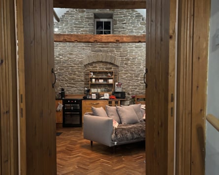 A view from the doorway of a room with stone walls, wooden beams and a cosy sofa
