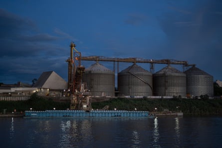 A night-time shot of a large barge in front of huge concrete silos.