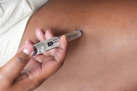 a person jabs themself with an injection pen of a drug