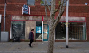A man walks in front of a derelict shopfront in Barrow-in-Furness, Cumbria