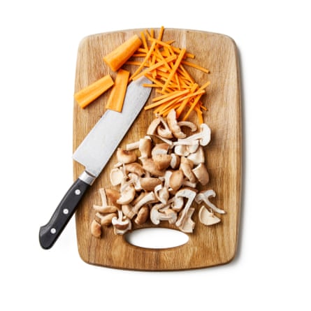 Chopping board with carrot and mushroom. Peel and cut the carrot into matchsticks and tear the mushrooms into bite-size pieces.