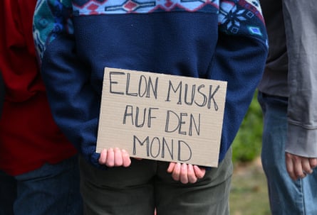 A woman holds a placard in Germany reading ‘Elon Musk Auf Den Moon’ (‘Elon Musk to the Moon’)