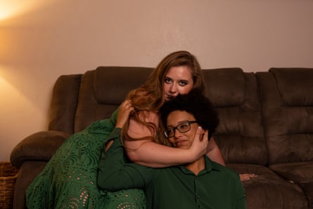 Priscilla sitting a brown sofa with her right arm cradling Kiara’s head. Kiara is sitting close to Priscilla on the floor, with her back against the soft and her right hand on Priscilla’s shoulder