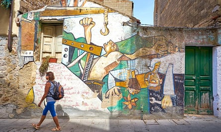 Female tourist walks past street art murals in Orgosolo, Sardinia, Italy.