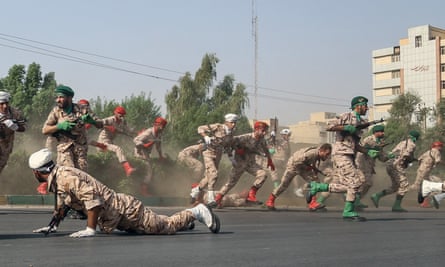 Iranian soldiers jump over a hedge at a street as they run for cover during the terrorist attack.