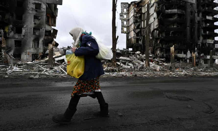 A woman walks in front of destroyed buildings in the town of Borodyanka