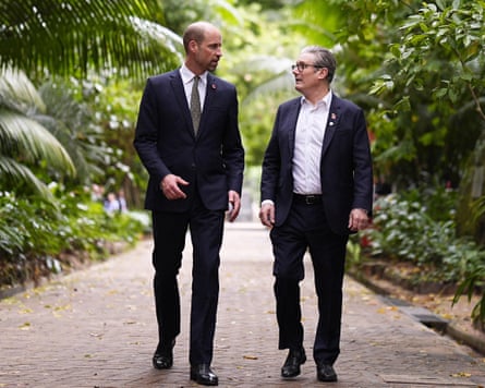 The Prince of Wales and Keir Starmer in discussion as they walk along pathway with vegetation either side