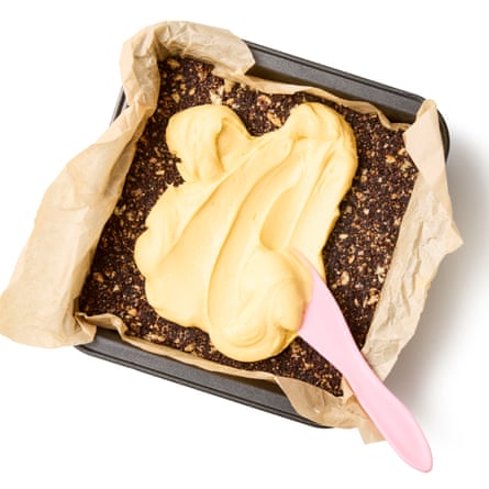 This picture shows a spatula or similar, spreading custard on top of the now chilled and firm biscuit base.