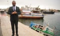James Cleverly walks past a sunken small boat during a visit to Lampedusa port.