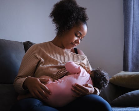 Candid moment of a mother feeding her multiracial baby daughter. Capturing a moment of quiet bonding and tenderness at home.