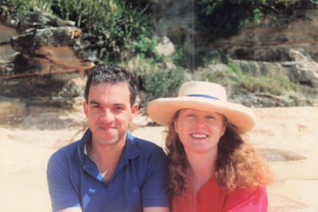 A photo of a man in a deep blue polo shirt and a woman in a red shirt and a broad brimmed hat on a beach