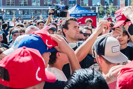 A man mobbed by people signing a hat