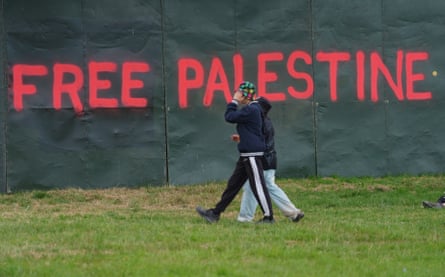 Two people walk past Free Palestine graffiti