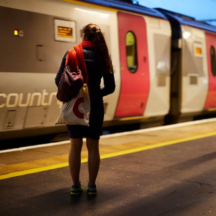 Lone woman with bags on shoulder facing arriving train.