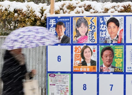 A woman walks past a panel of candidates near a polling station in Tokyo