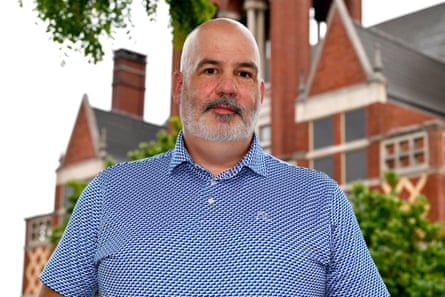 a man in a blue shirt in front of a red brick building