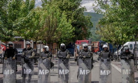 A line of military police in riot gear on a road in Zvecan